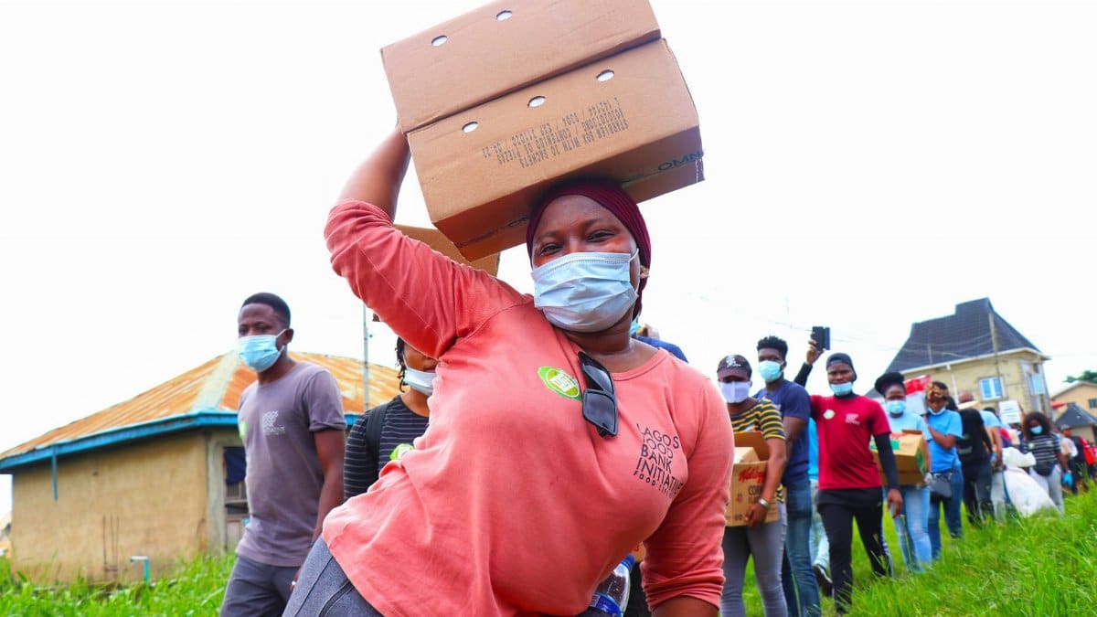 Volunteers wearing masks distribute aid boxes during a community support event.