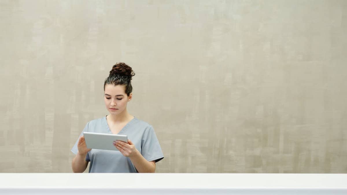 Caucasian woman in uniform using a tablet at a modern reception desk.