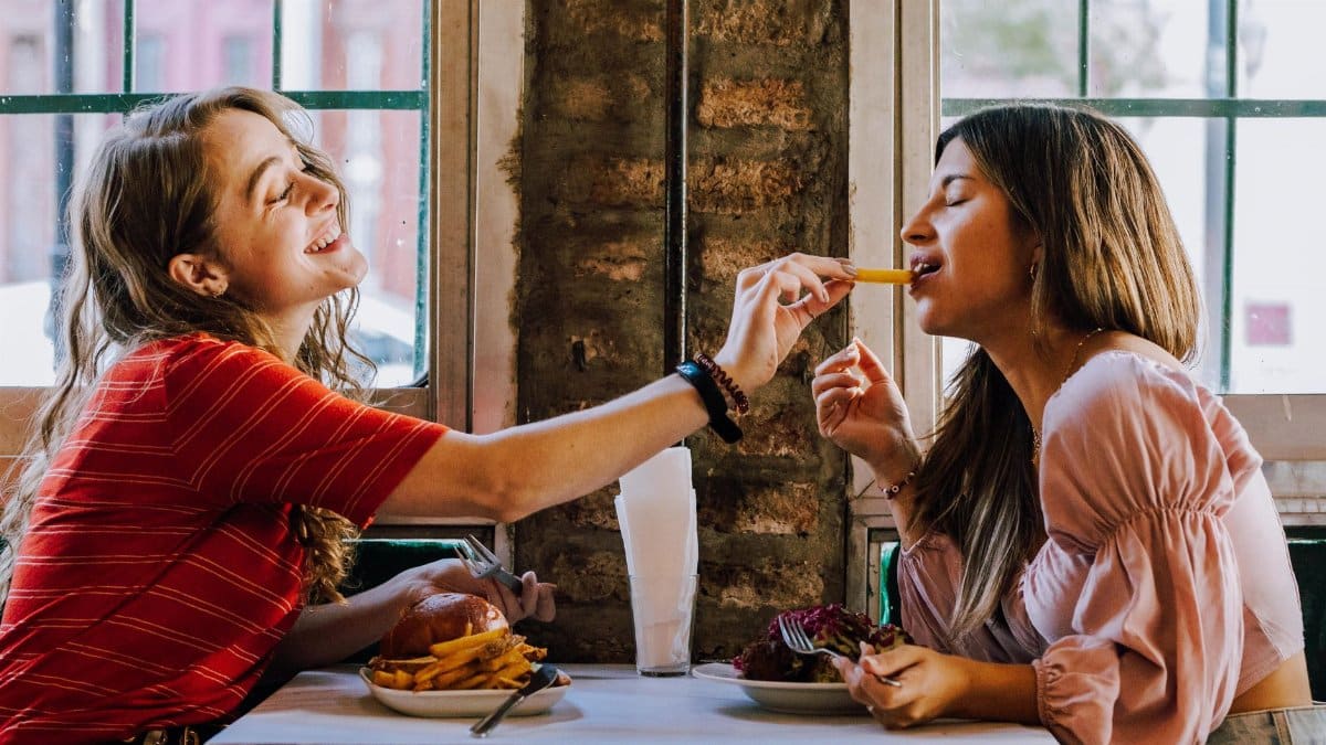 Friends sharing a joyful meal with fries at a cozy Buenos Aires diner.