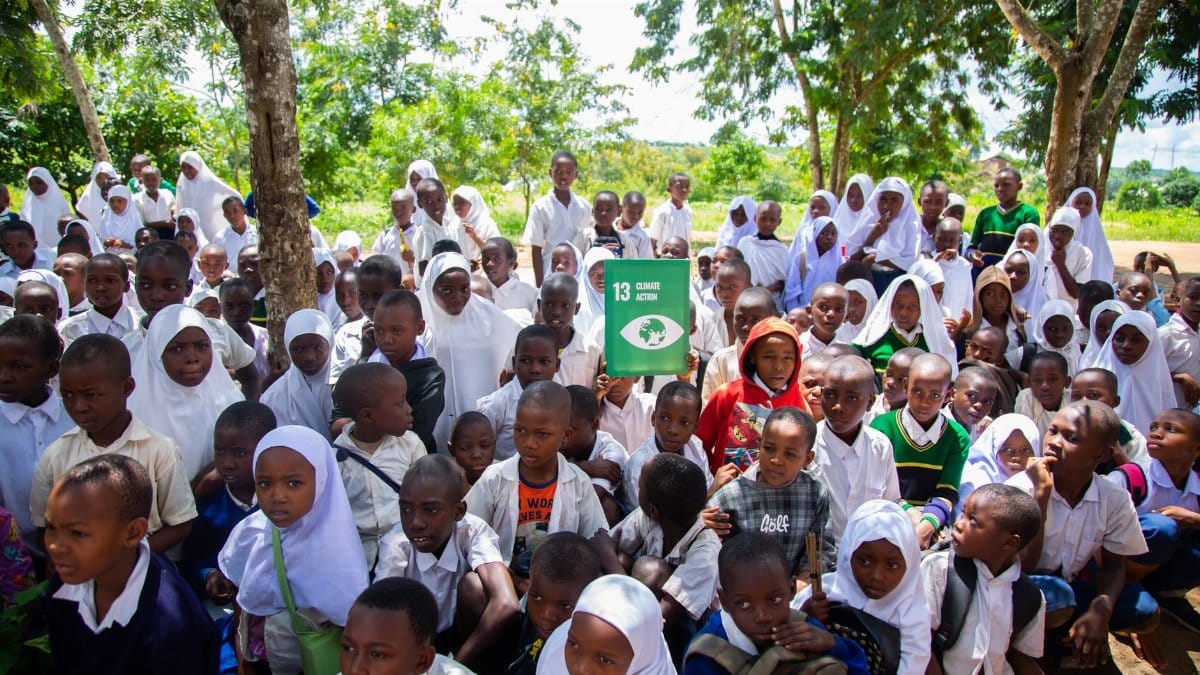 Large group of children wearing uniforms outdoors, promoting climate action