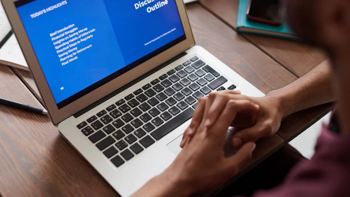 A person viewing a business presentation on a laptop screen, ideal for online learning and work settings.