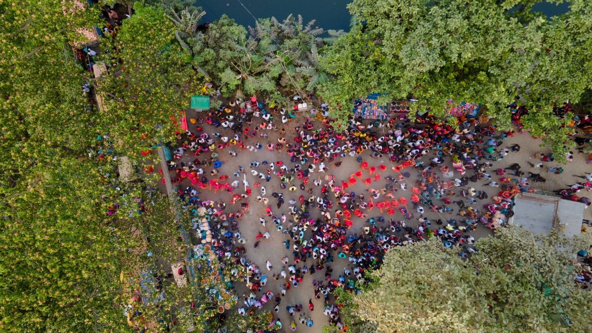 Aerial view of a lively outdoor festival surrounded by lush greenery and a waterbody.