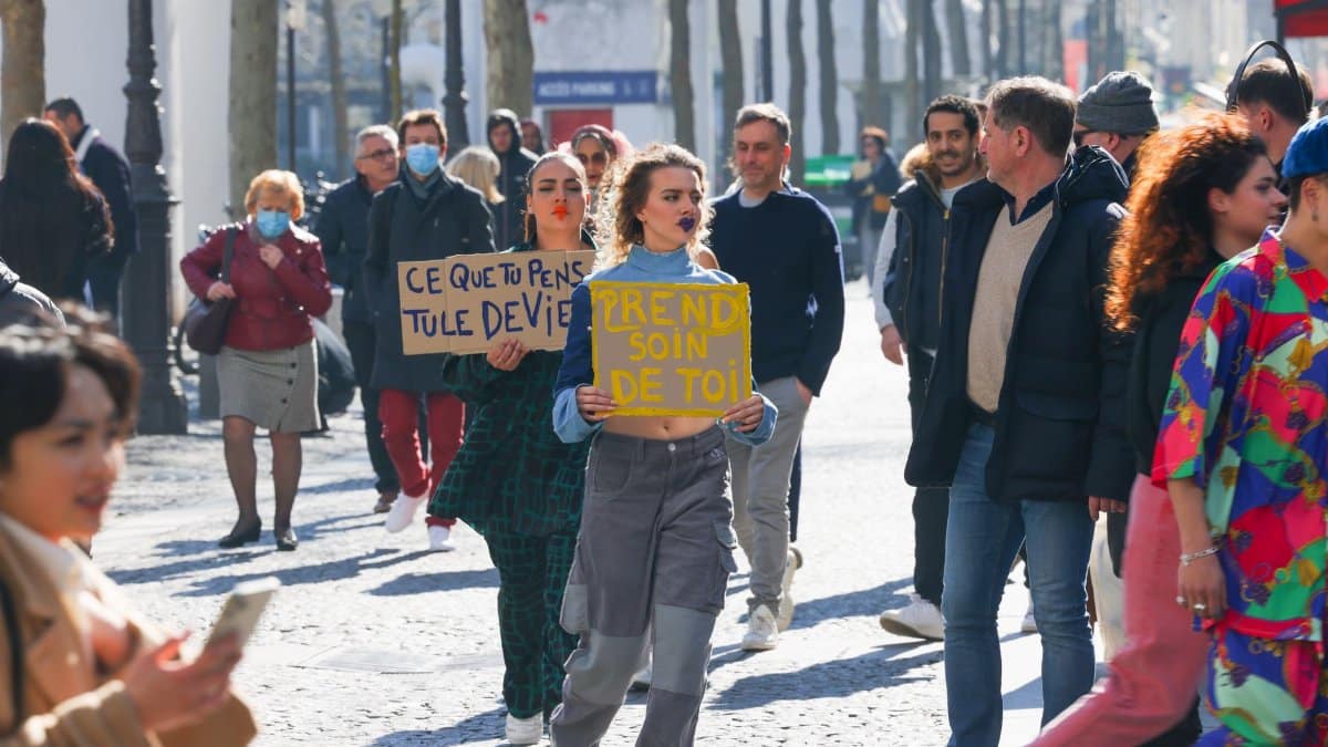 Women holding protest signs on a busy street advocating social issues.