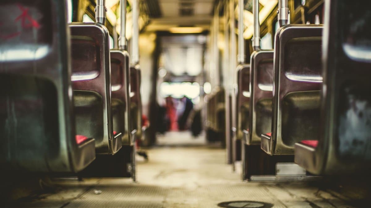 Interior view of an empty public transport vehicle, focusing on rows of seats and warm lighting.