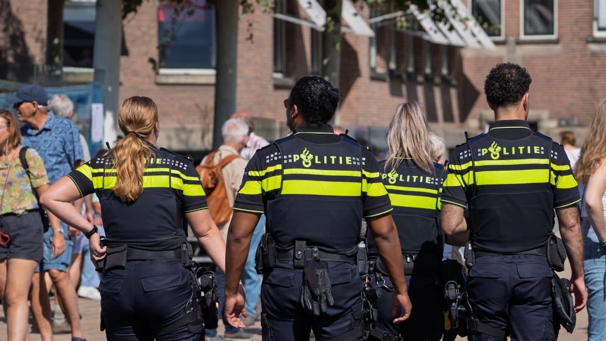 Dutch police officers patrolling a busy urban area during daytime, ensuring public safety.