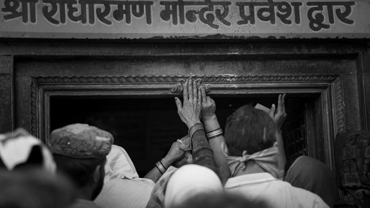 Hands reaching out in prayerful devotion at the entrance of Shri Radha Raman Temple, Vrindavan.