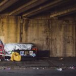 A gritty urban underpass in Philadelphia with signs of homelessness and American flag.