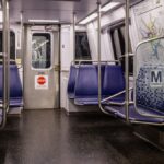 Interior view of an empty Washington DC Metro train car with blue seats and map display.