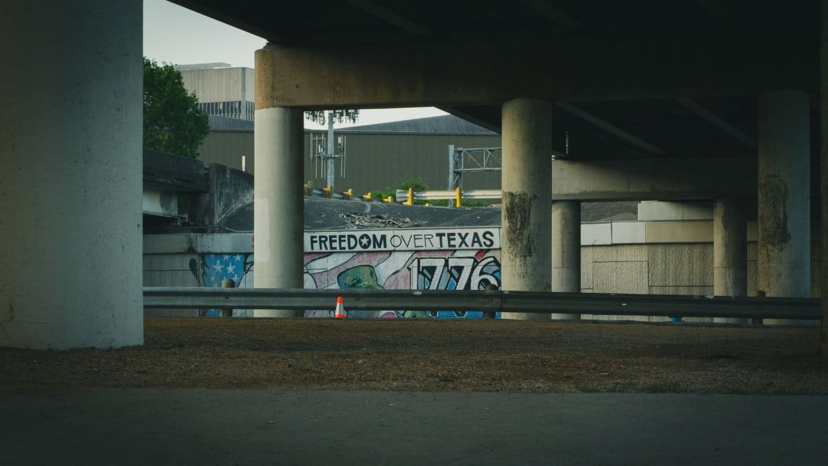 Graffiti art featuring 'Freedom Over Texas' beneath a concrete bridge in Houston.