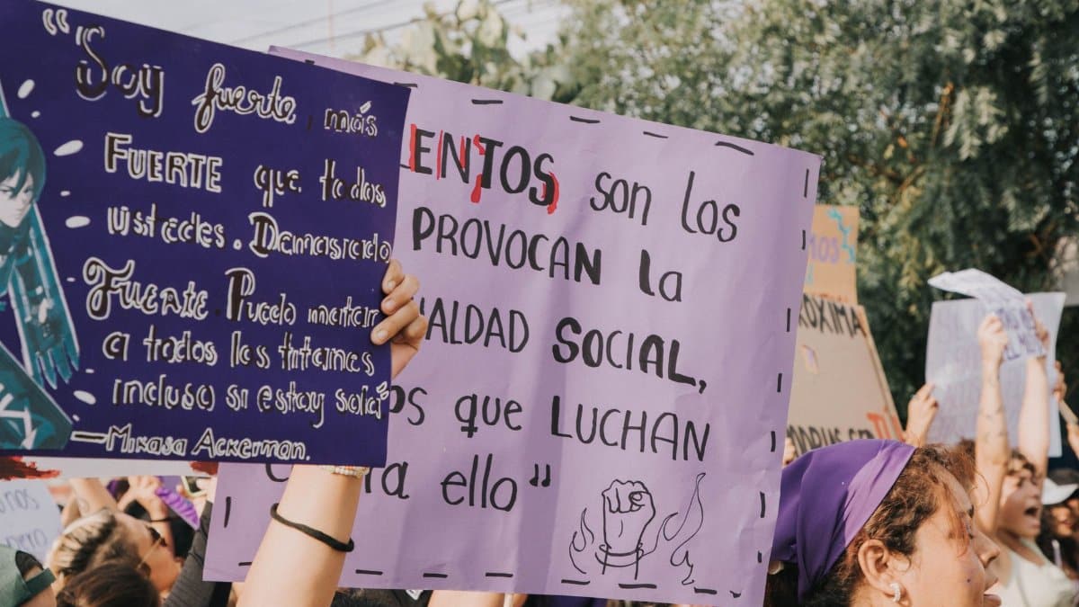 Women holding protest signs during a social justice demonstration outdoors.