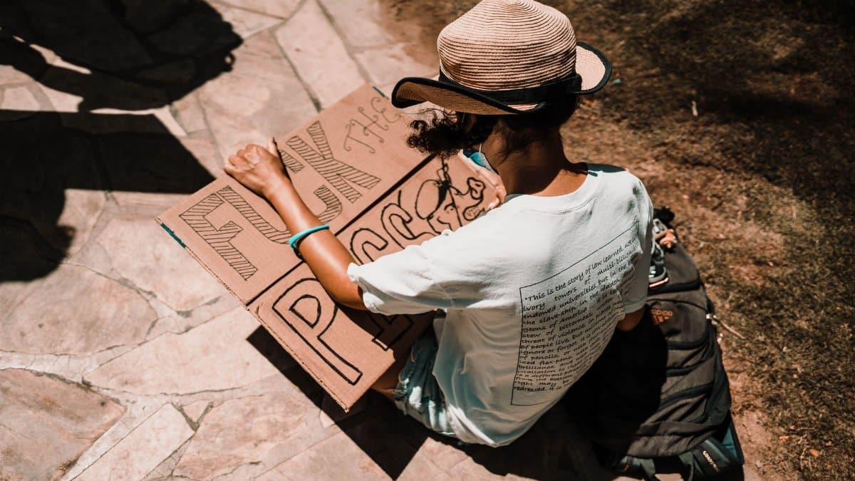 Person sitting on pavement holding a protest sign in Honolulu, Hawaii.