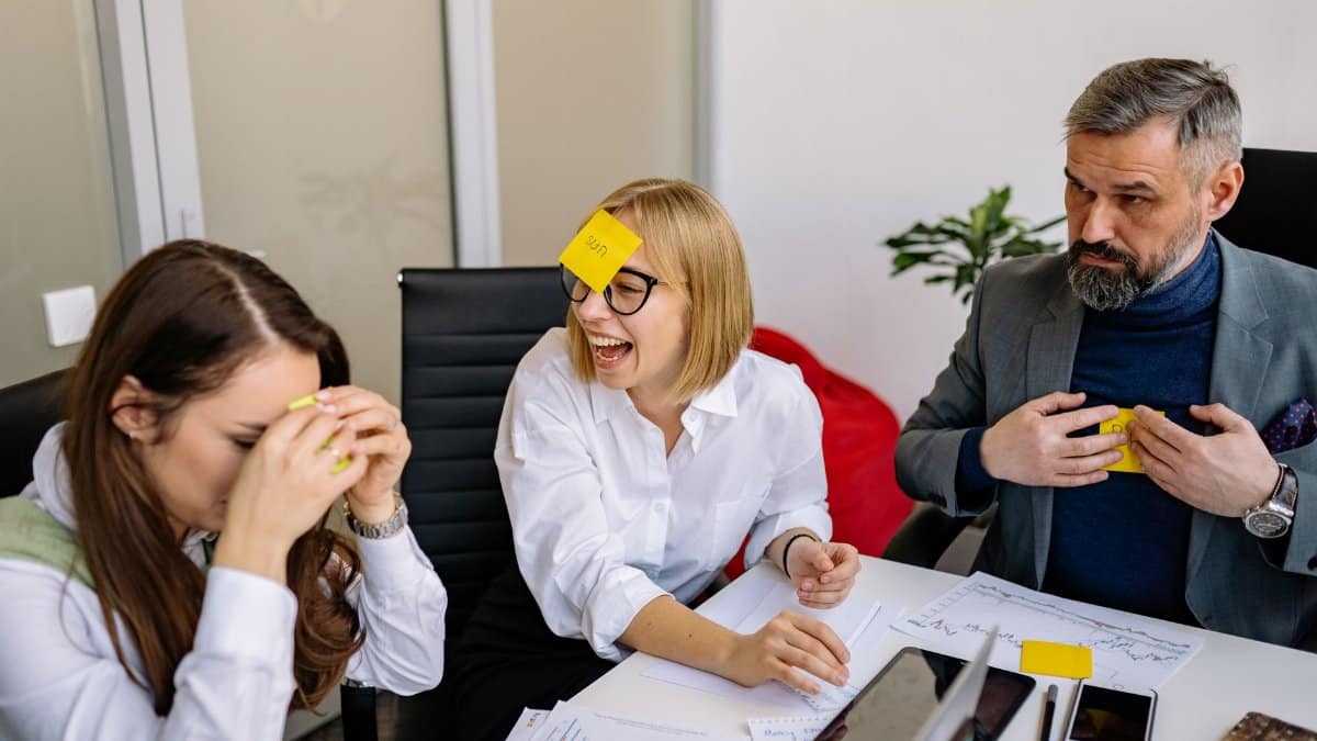 Business colleagues engaging in a fun team building activity with sticky notes in a conference room.