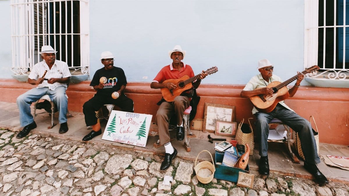 Cuban street musicians playing guitars and maracas, creating lively music on a vibrant city street.