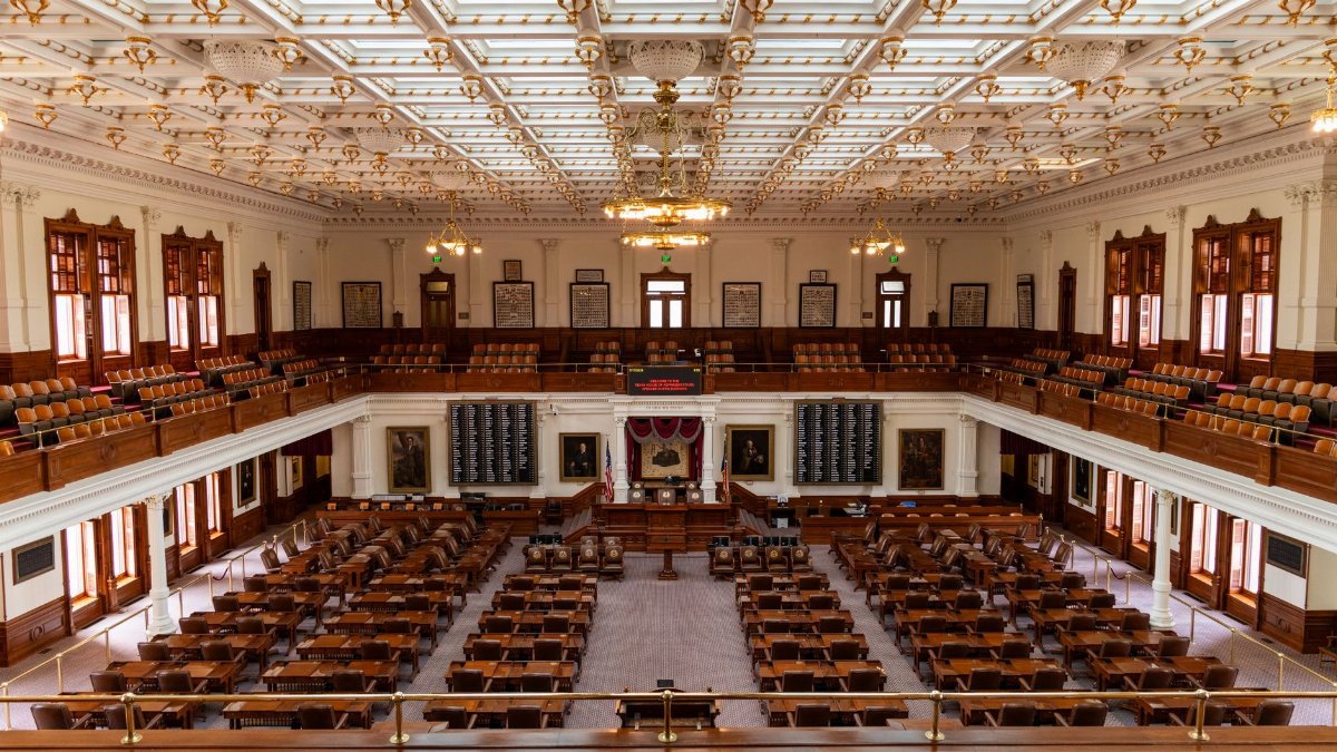 Spacious interior of the Texas State Capitol House Chamber with seating and elaborate ceiling.