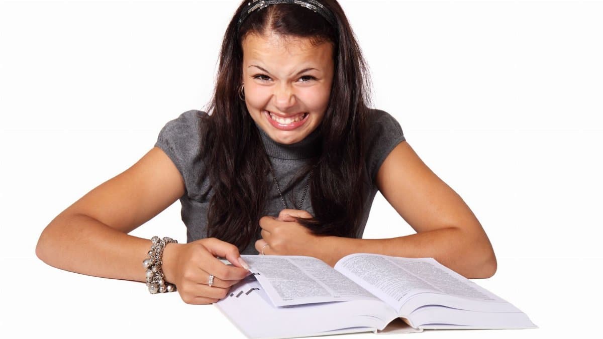 A woman with a funny expression reading a book, conveying humor and amusement.