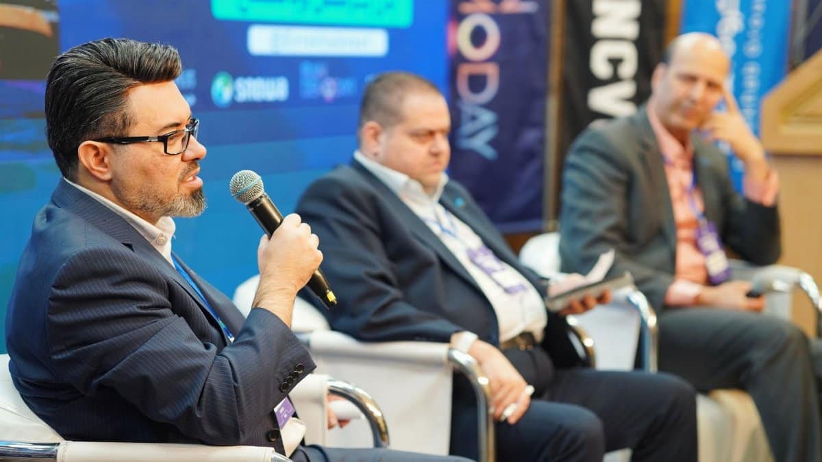 Three men engaged in a panel discussion at a professional conference.