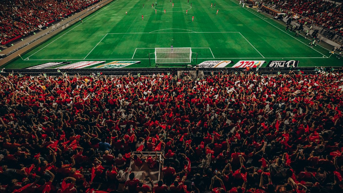 Aerial shot of a lively football match with enthusiastic fans in a packed stadium.