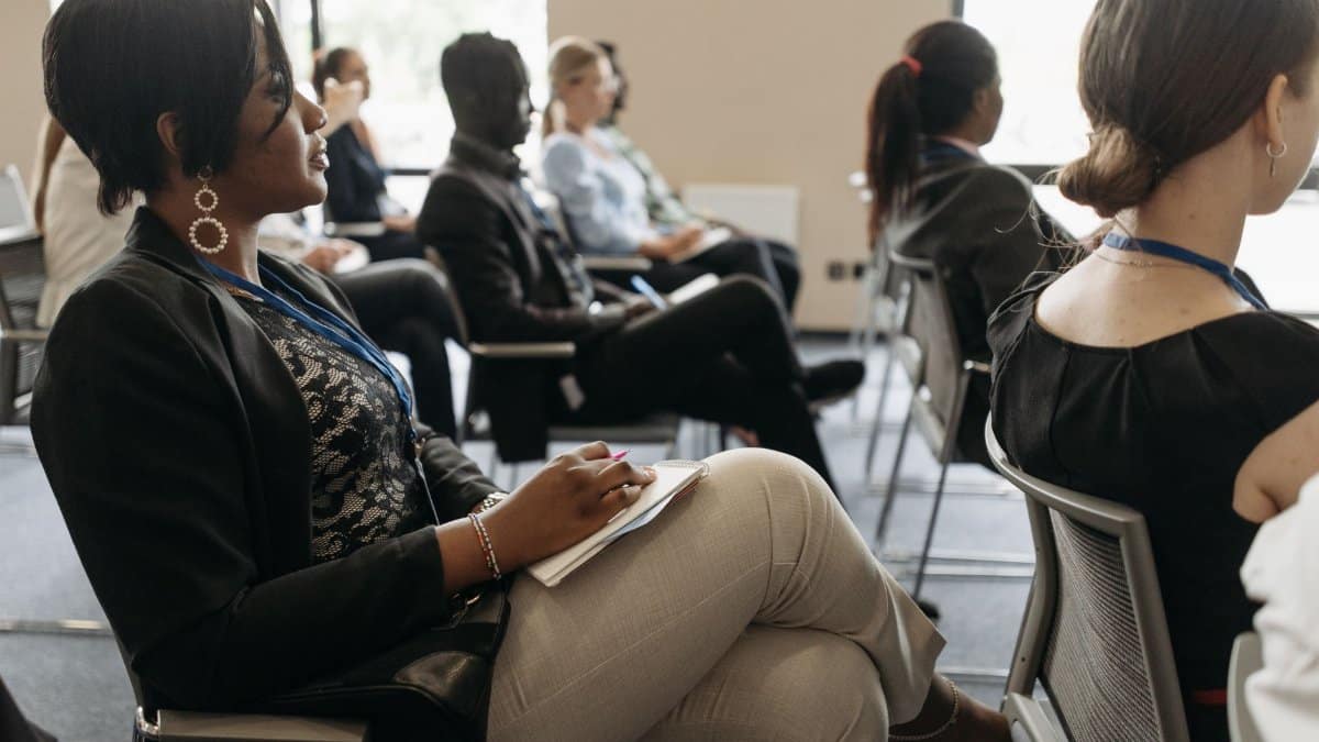 Participants attentively listening in a business conference room, highlighting diversity.
