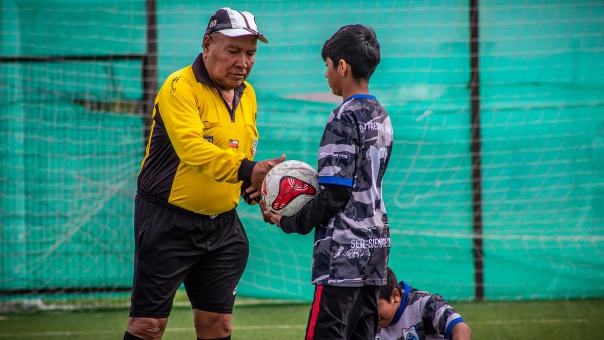 An adult coach and young players during a soccer practice session outdoors in Chile.