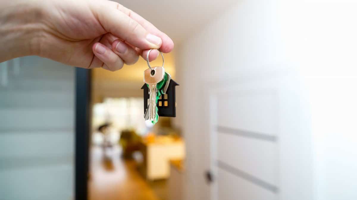 A hand holding house keys inside a modern apartment, symbolizing new property ownership or rental.