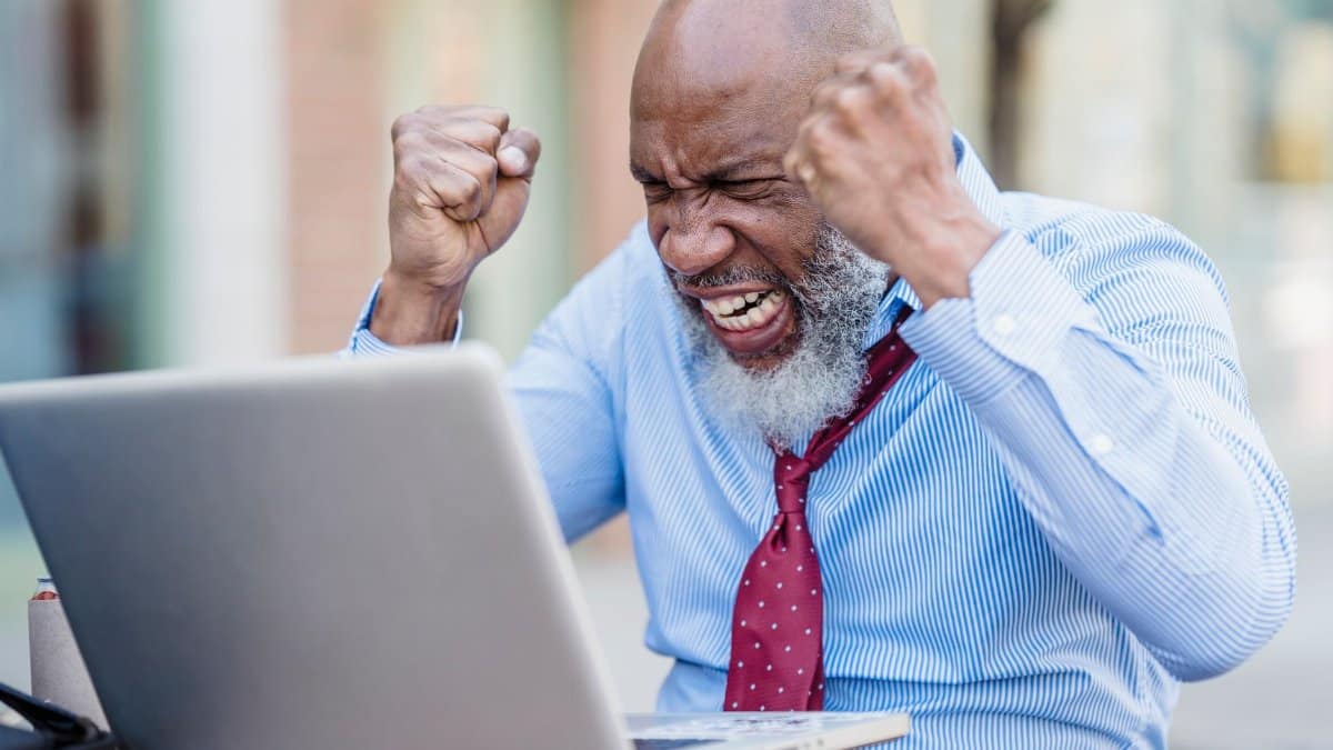 African American businessman showing frustration working on a laptop outdoors.