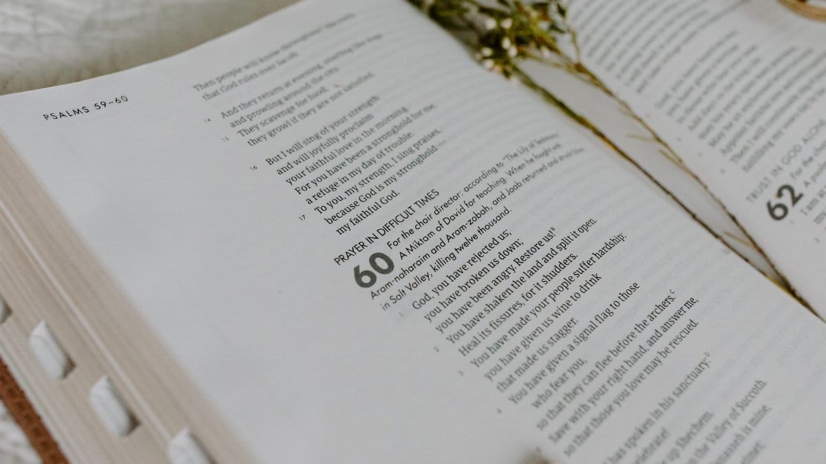 Close-up of an open Bible showing Psalm 60 with dried flowers.