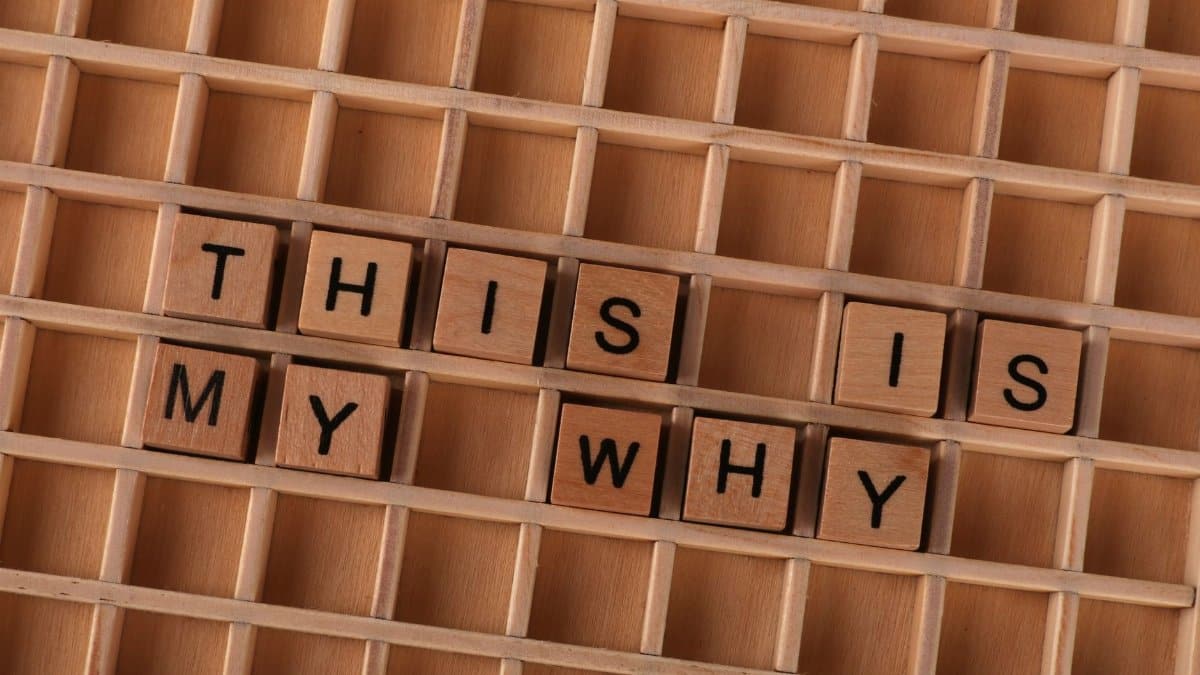 Scrabble tiles arranged to spell 'This Is My Why' on a wooden grid. Perfect for motivation and introspection themes.