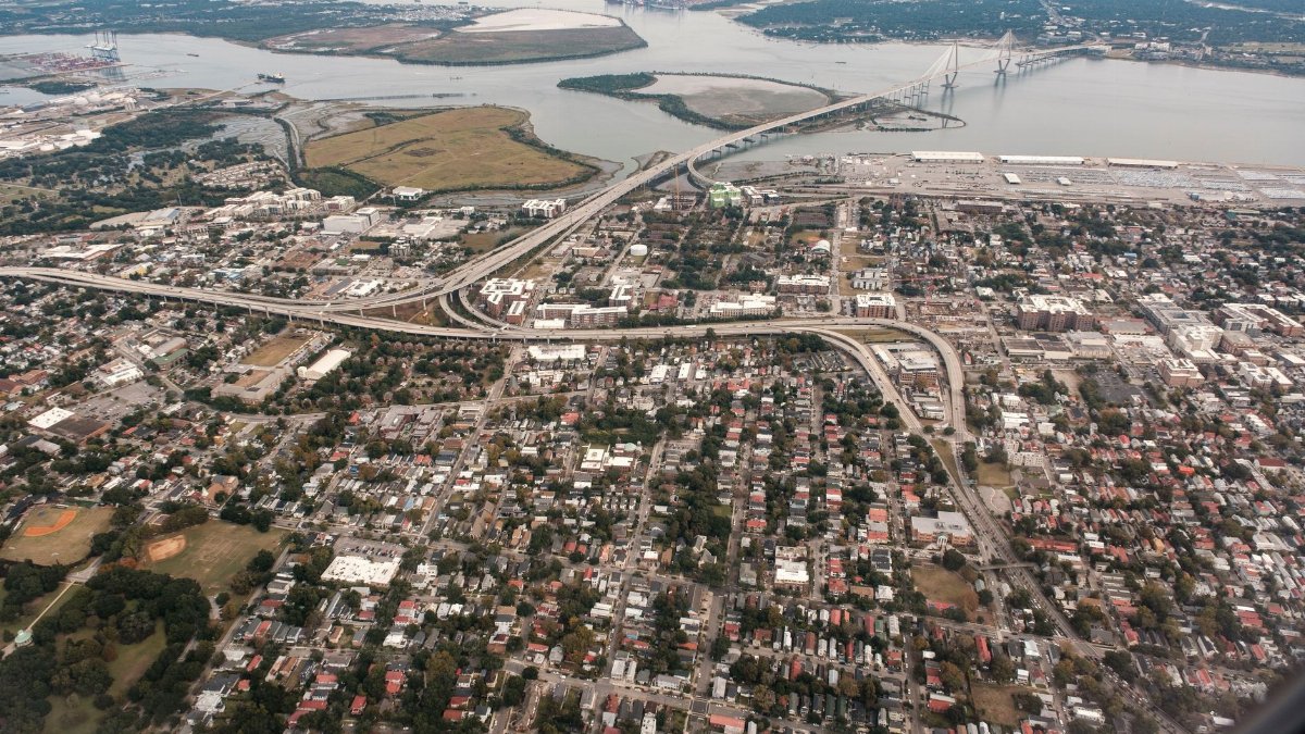 A stunning aerial photograph of Charleston, South Carolina, showcasing the city's layout and the iconic Arthur Ravenel Jr. Bridge.