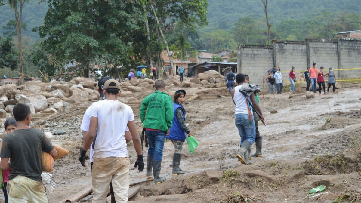 People navigate a muddy terrain in Mocoa, Colombia, post-flood recovery efforts.