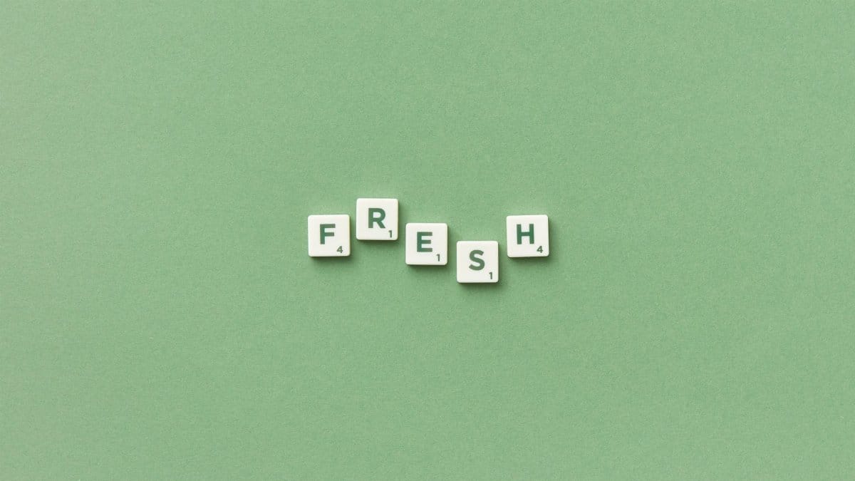 Scrabble tiles spelling 'FRESH' on a green background, perfect for word games or minimalist design themes.