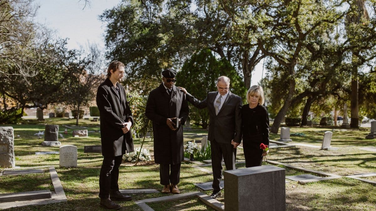 A solemn funeral gathering in a cemetery, capturing an emotional moment of remembrance.