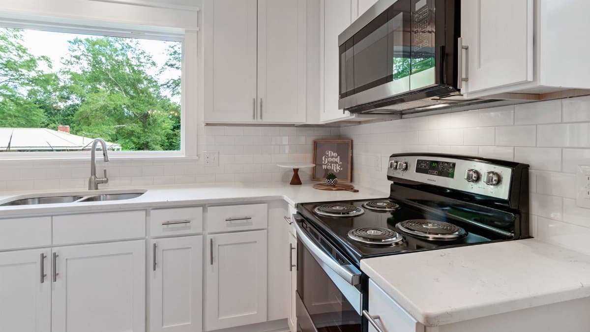 Bright modern kitchen with white cabinetry and stainless steel appliances.