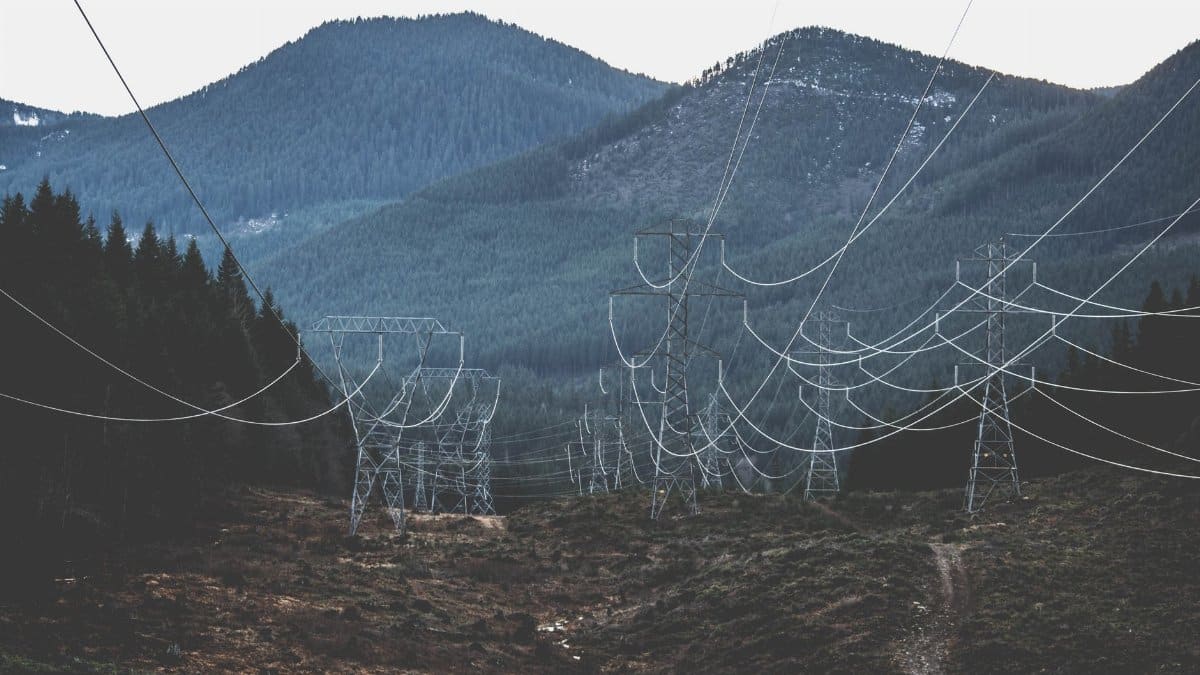 Power lines stretch across a rugged mountain landscape, showcasing infrastructure in nature.