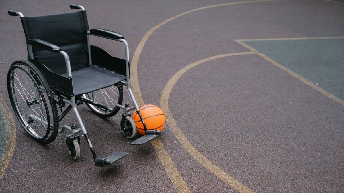 Wheelchair beside a basketball on an outdoor court highlights accessibility and sports.