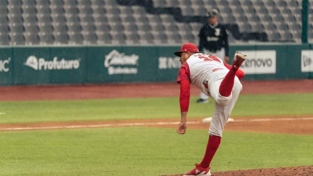 A baseball pitcher throws a pitch in a rainy stadium during a game.