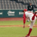 A baseball pitcher throws a pitch in a rainy stadium during a game.