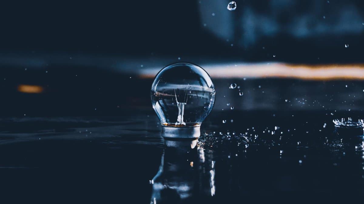Close-up of a light bulb reflecting in water, capturing creative splashes and droplets.