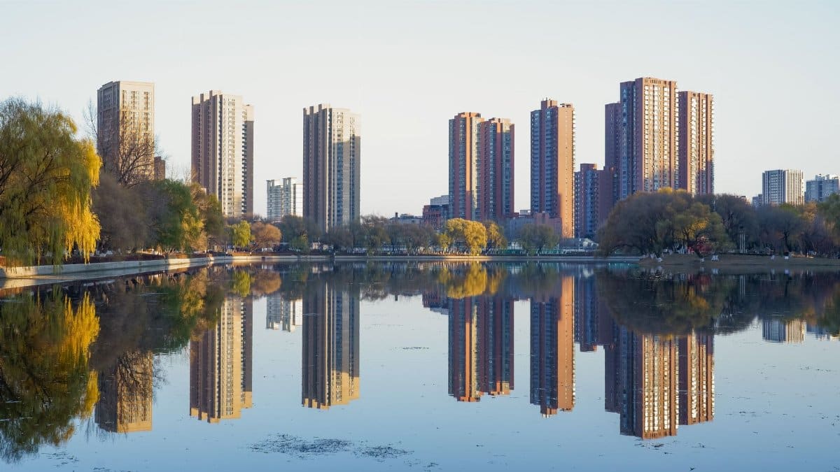 Stunning skyline of Shenyang reflected in a serene lake, capturing urban symmetry and autumn colors.