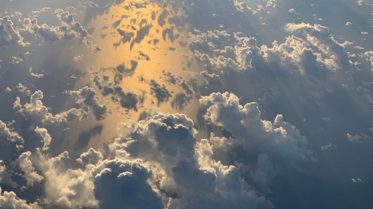 Stunning aerial photo of clouds reflecting sunlight over the ocean, creating a golden display.
