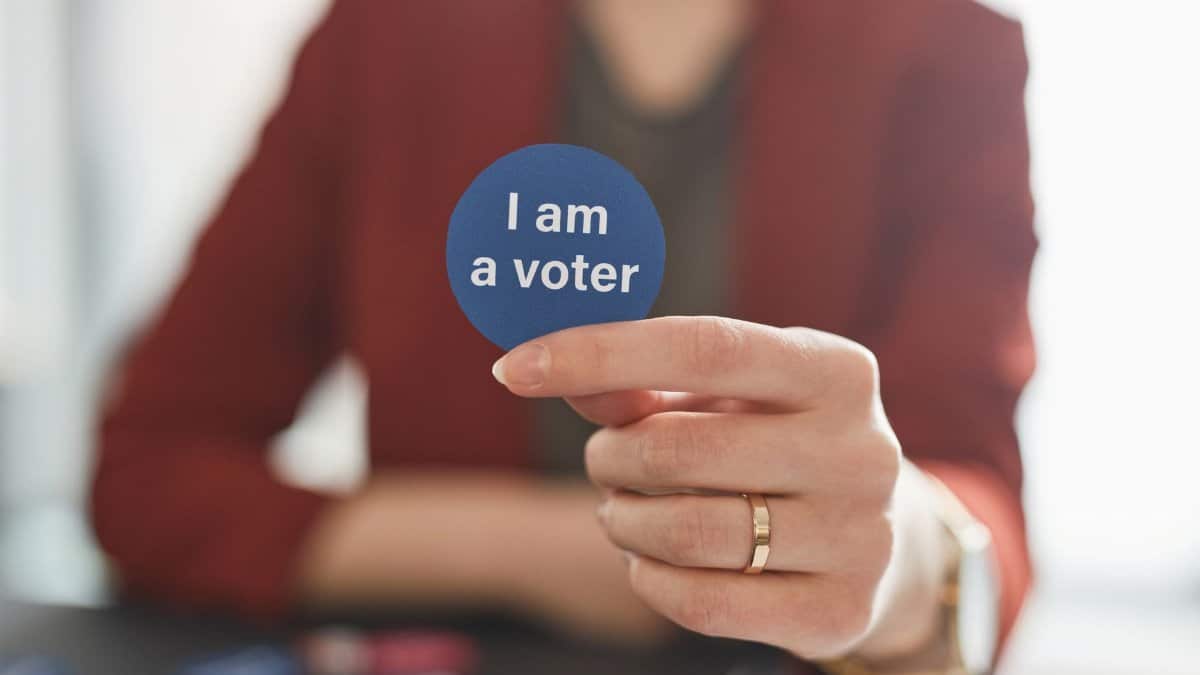 A person holds a voter badge, symbolizing civic responsibility and participation.