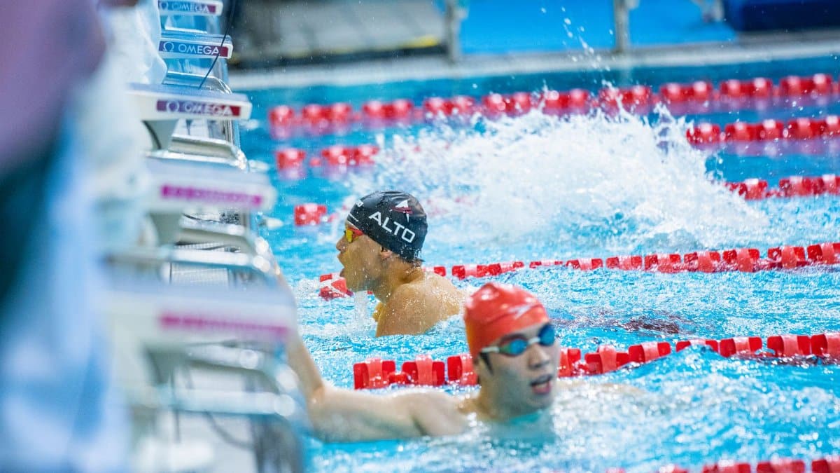Two adult male swimmers racing in an indoor pool, featuring competitive spirit and athleticism.