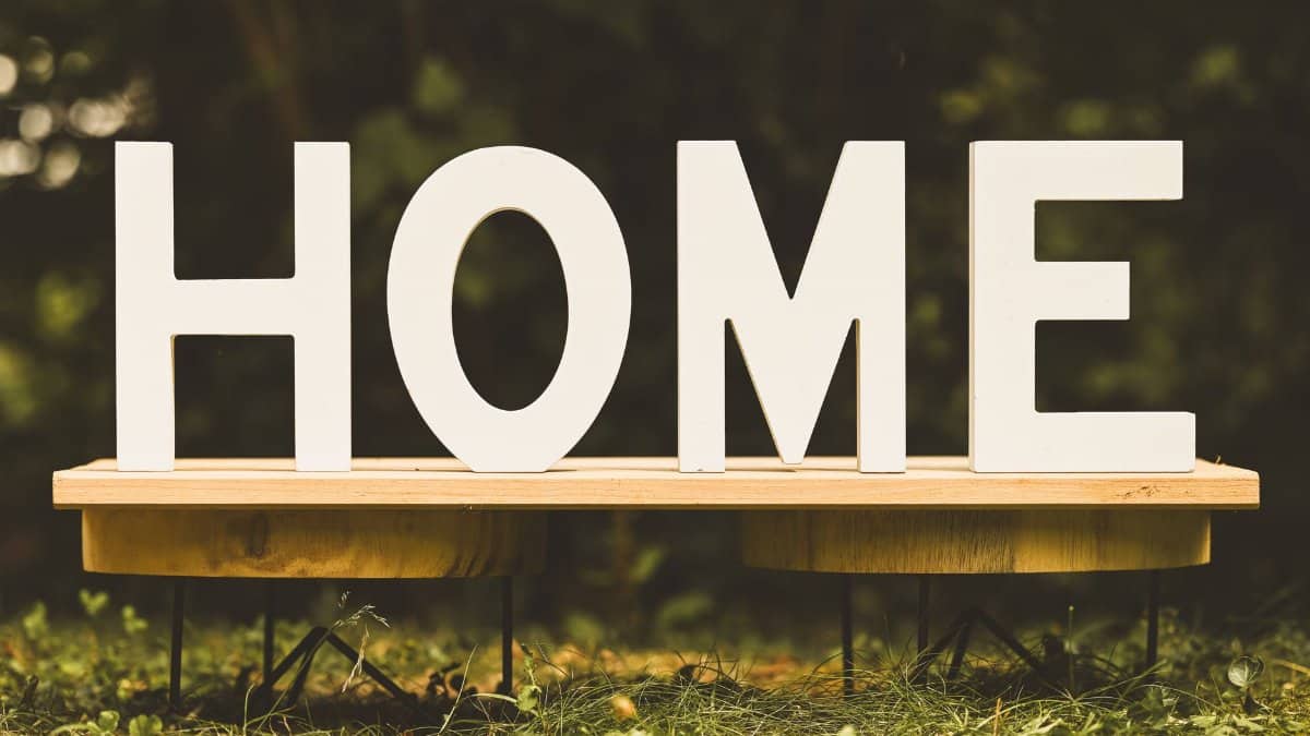 Artistic display of wooden letters spelling 'HOME' on a bench outdoors.