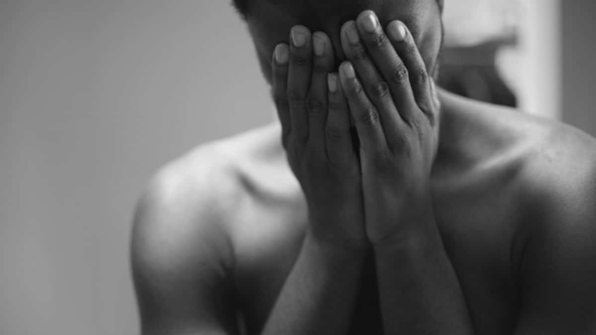 Black and white portrait of a man in distress, conveying deep emotions and vulnerability.