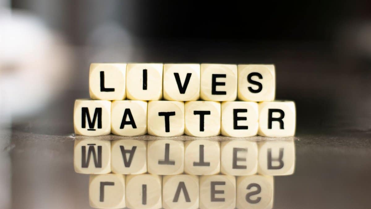 Cubes spelling out 'Lives Matter' with reflection on a smooth surface.