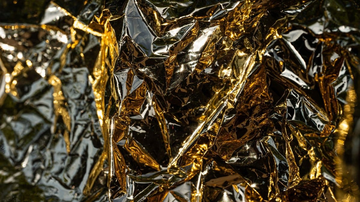 A close-up, detailed view of crumpled gold foil with intricate reflections and textures.