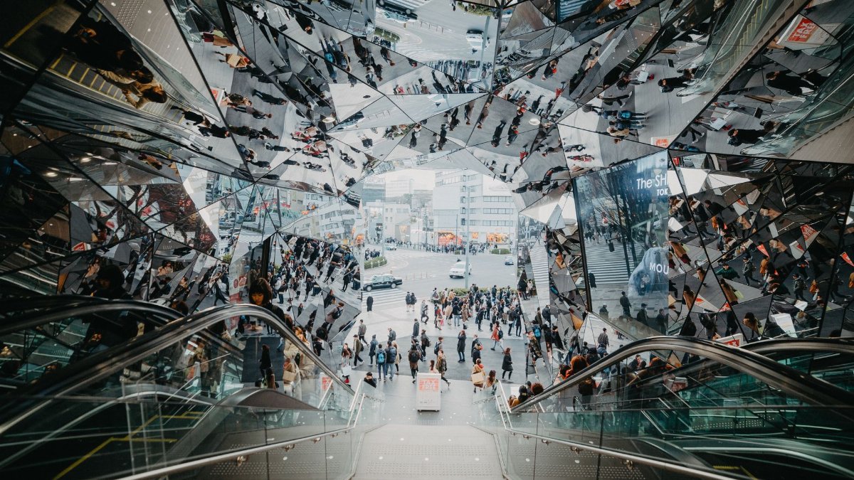 High angle view of escalators and modern architecture in a Tokyo shopping mall with mirrored reflections.