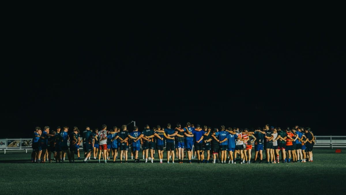 Sports team huddle on a field at night, fostering teamwork and unity.