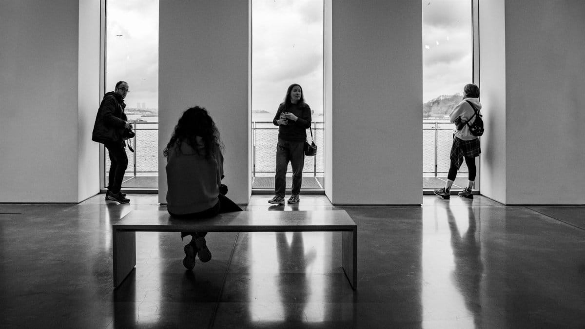 A moody black and white photo capturing silhouettes and reflections in an Istanbul art gallery.