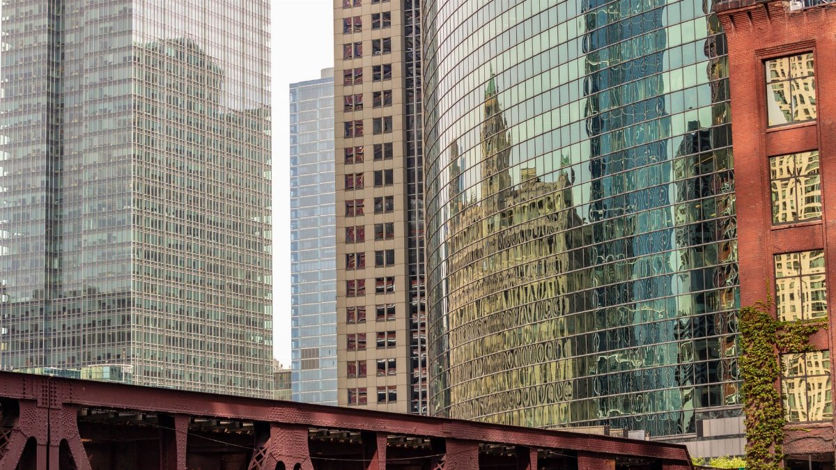 Modern urban architecture with reflections on glass facades showcasing city skyline.