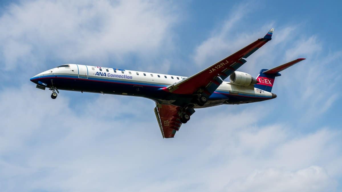 A mid-air shot of an ANA Connection jet with blue and white livery soaring through a clear sky.